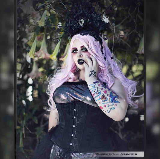 Plus size model with pink hair and black headdress wearing the Black Rose Brocade Hourglass Cincher over a silver and black dress.
