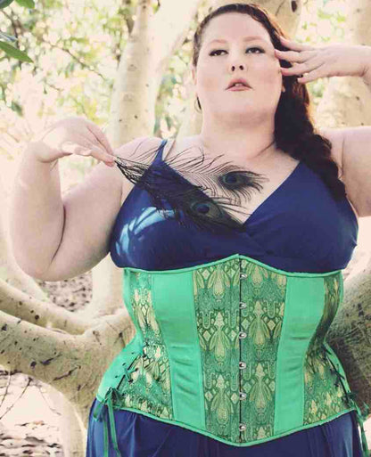 A plus size model wearing the Emerald & Gold Brocade Hourglass Cincher over a dark blue dress.