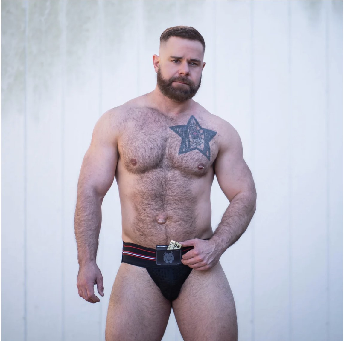 A model wearing the Gruff Pup Pocket Jockstrap with money sticking out of the front pocket, front view.