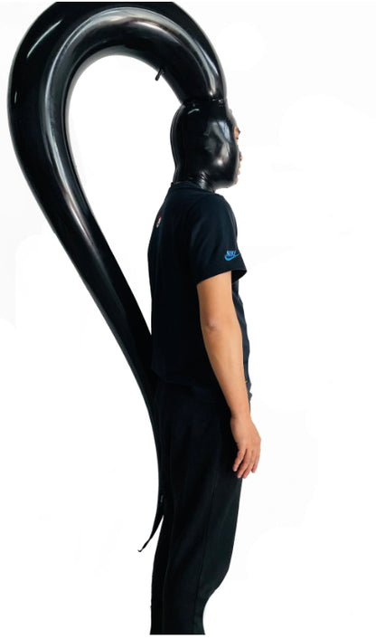 A model dressed in black wearing the Inflatable Single Pony Tail Latex Hood, side view.
