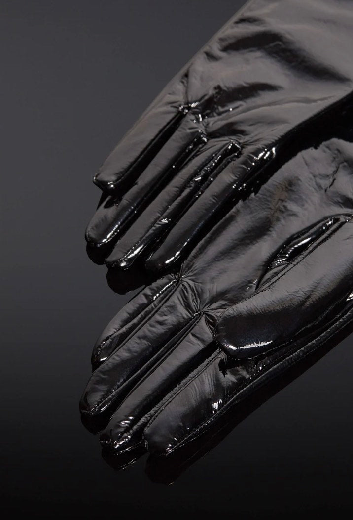 The Patent Forearm Gloves lying flat on a black surface.