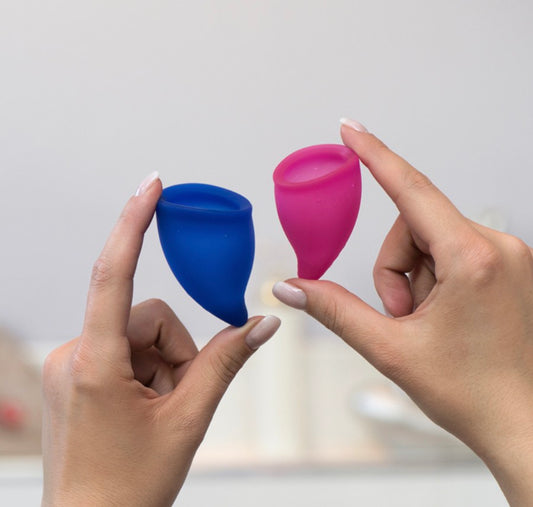 A pair of hands holding the two sizes of Fun Cup Menstrual Cups.