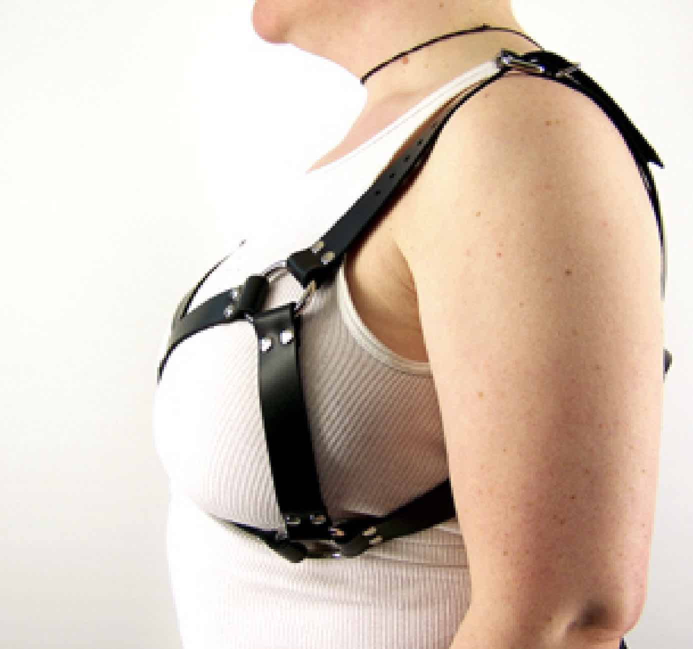 The side view of a woman wearing the thin Leather Bra Harness over a white tank top.
