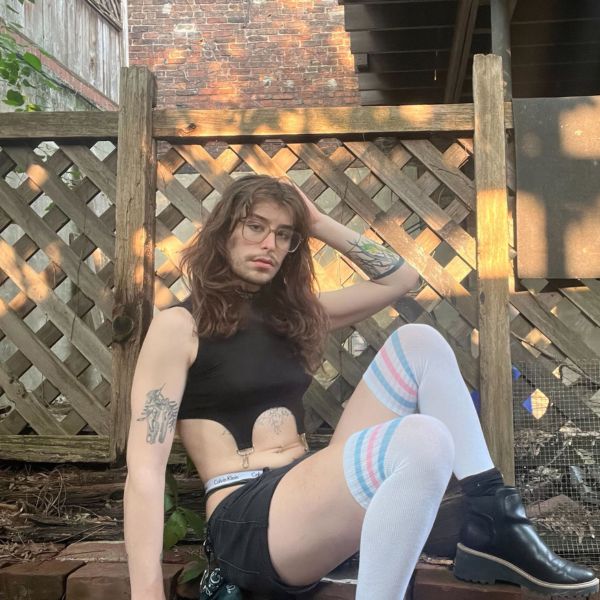 Model sitting wearing Trans Pride Over the Knee Athletic Socks with one knee up and other down