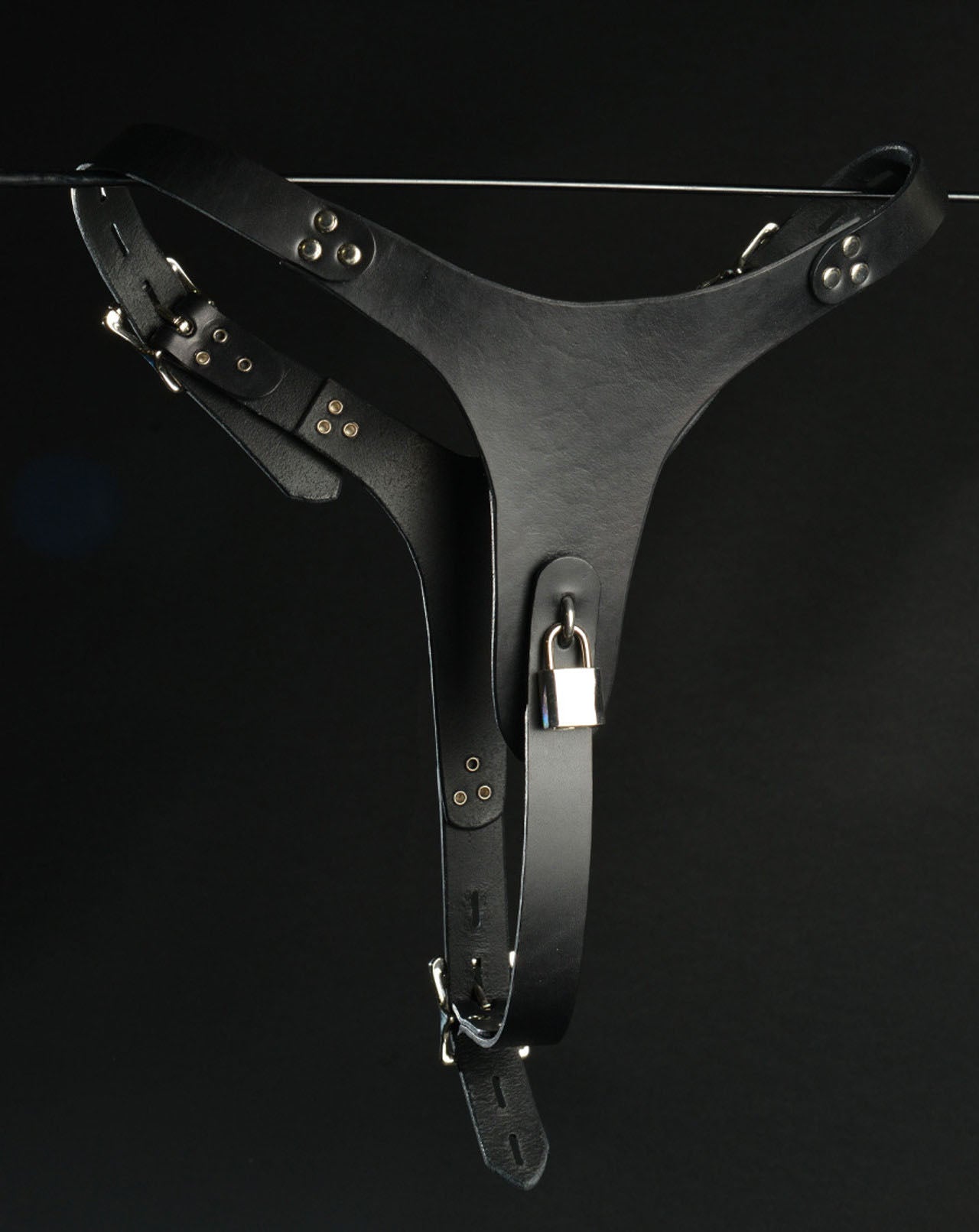 The Adjustable Leather Vaginal Chastity Belt hanging on a metal rod, front view.