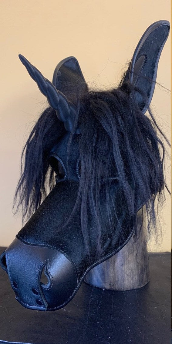 Black leather unicorn mask on a mannequin, front view.