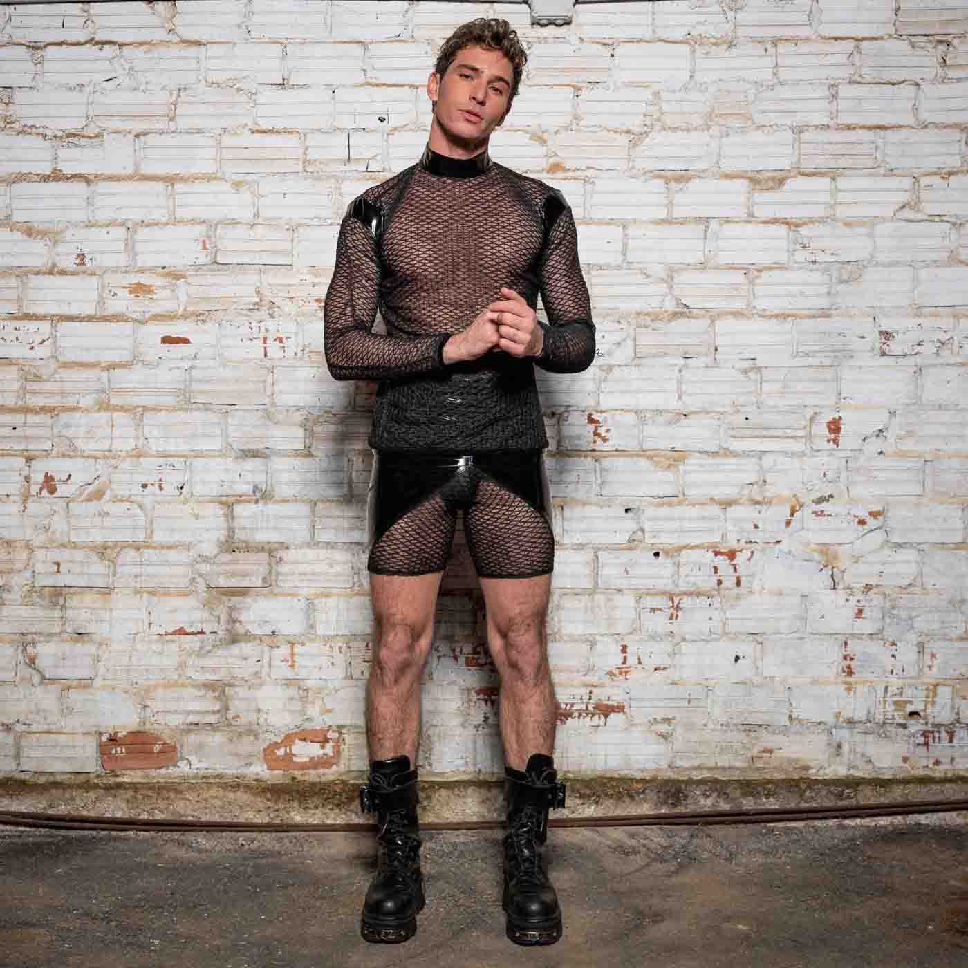 A model wearing the Leif Net & PatentT-Shirt with black patent and net shorts and black combat boots, front view.