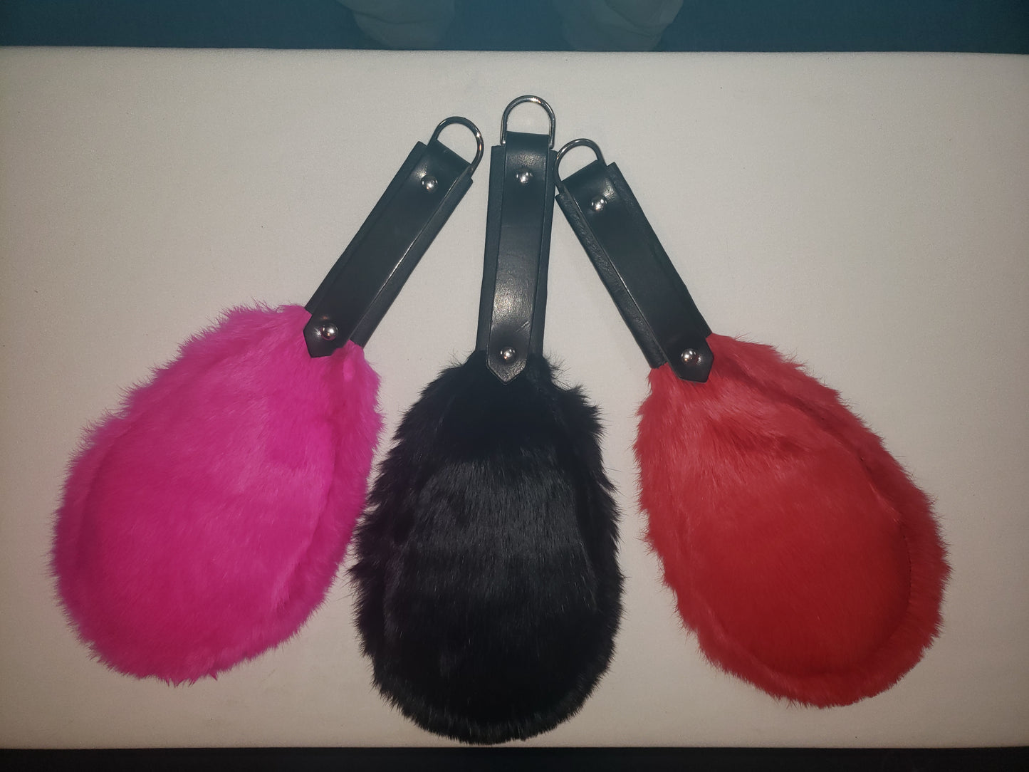 Rabbit fur covered round paddle. Padded fur side shown in available colors Pink, Black and Red.