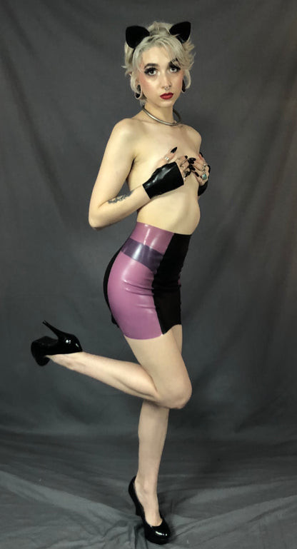 A feminine model wearing cat ears, holding black latex gloved hands over their breasts and showing the right side of the black and magenta Latex Girdle Mini Skirt.