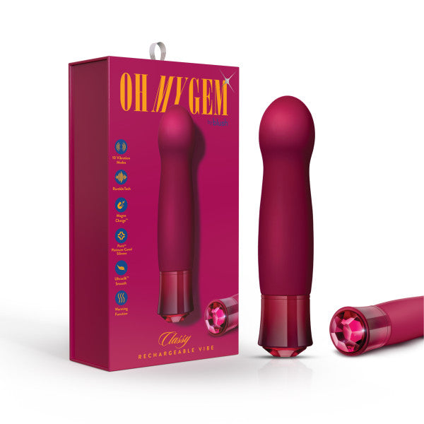 The Oh My Gem Classy Garnet Vibrator standing upright next to its packaging and another Oh My Gem Classy Garnet Vibrator lying on its side exposing the diamond decoration on its end.