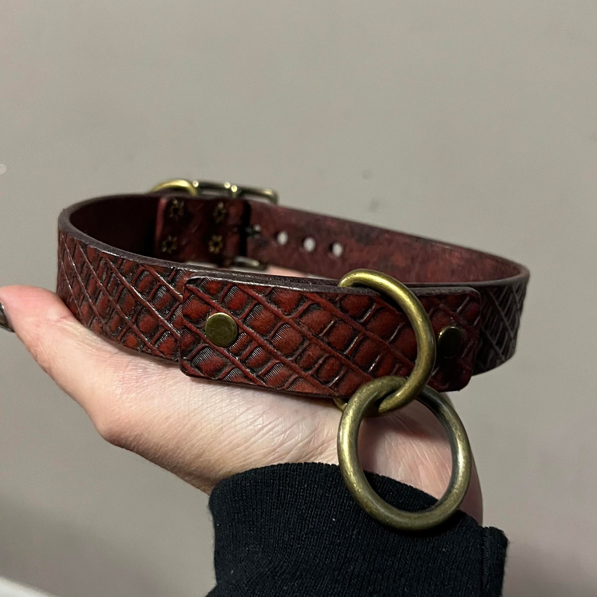 model hand holding hand tooled brown leather collar with front o-ring