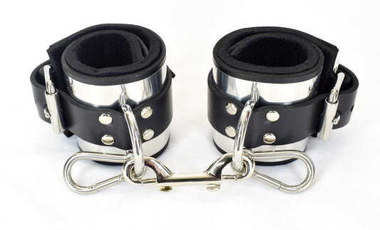Metal band bondage cuffs connected with snap closure against white background