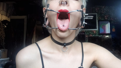 A model wearing jennings steel medical mouth gag, pierced tongue sticking out.