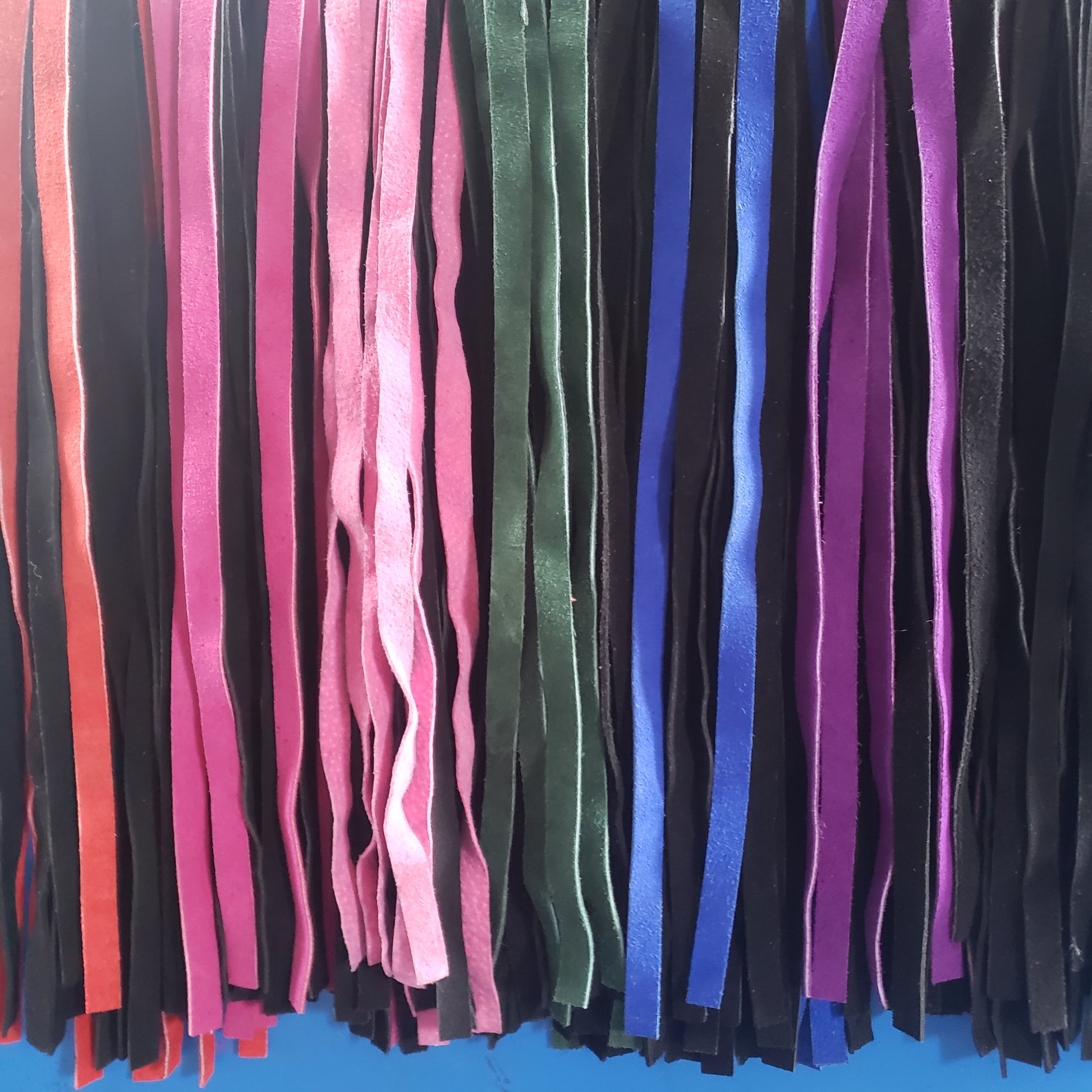 An assortment of colors of the Suede Finger Loop, Flogger in black, purple, green, blue and red.