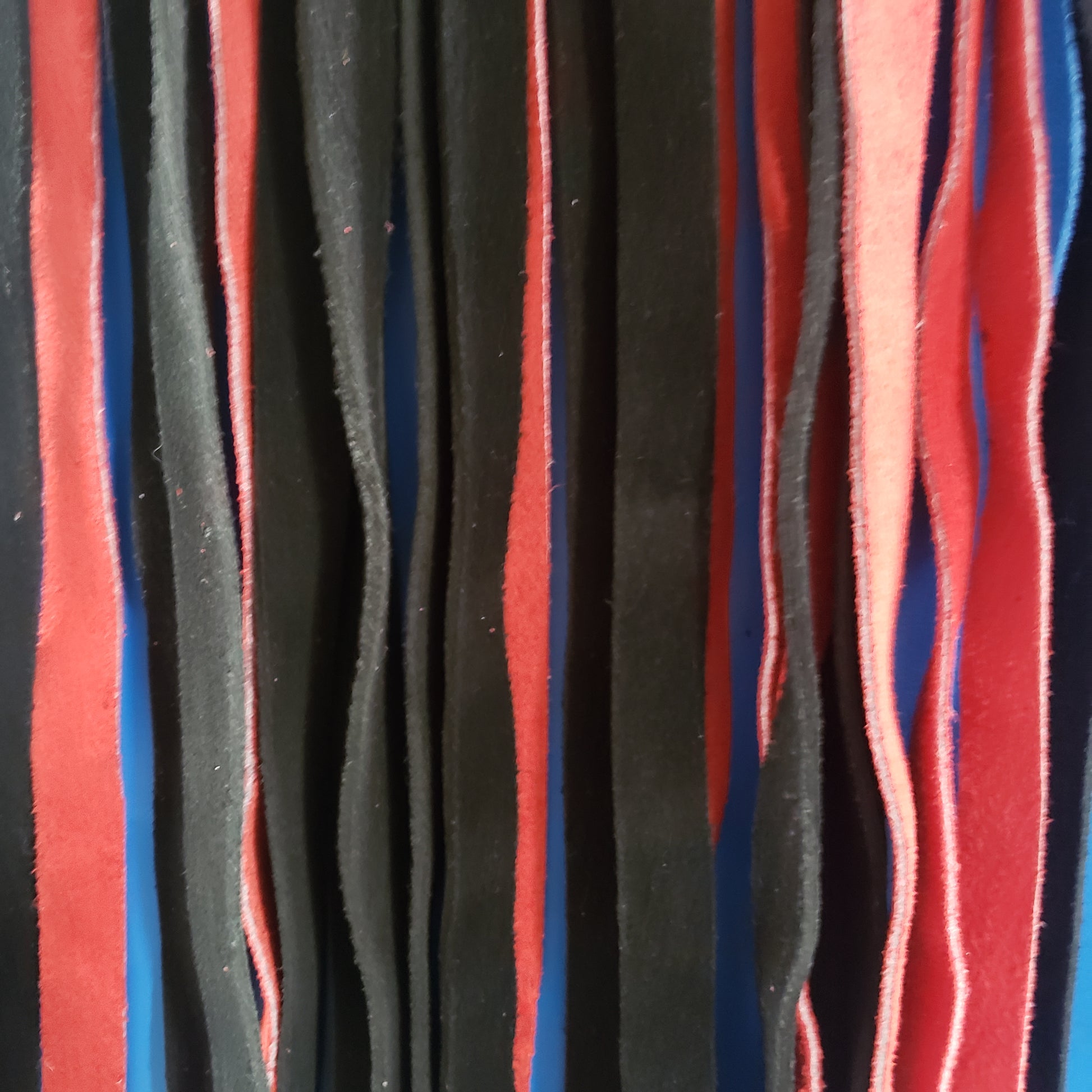 A closeup of the red and black suede finger loop flogger.