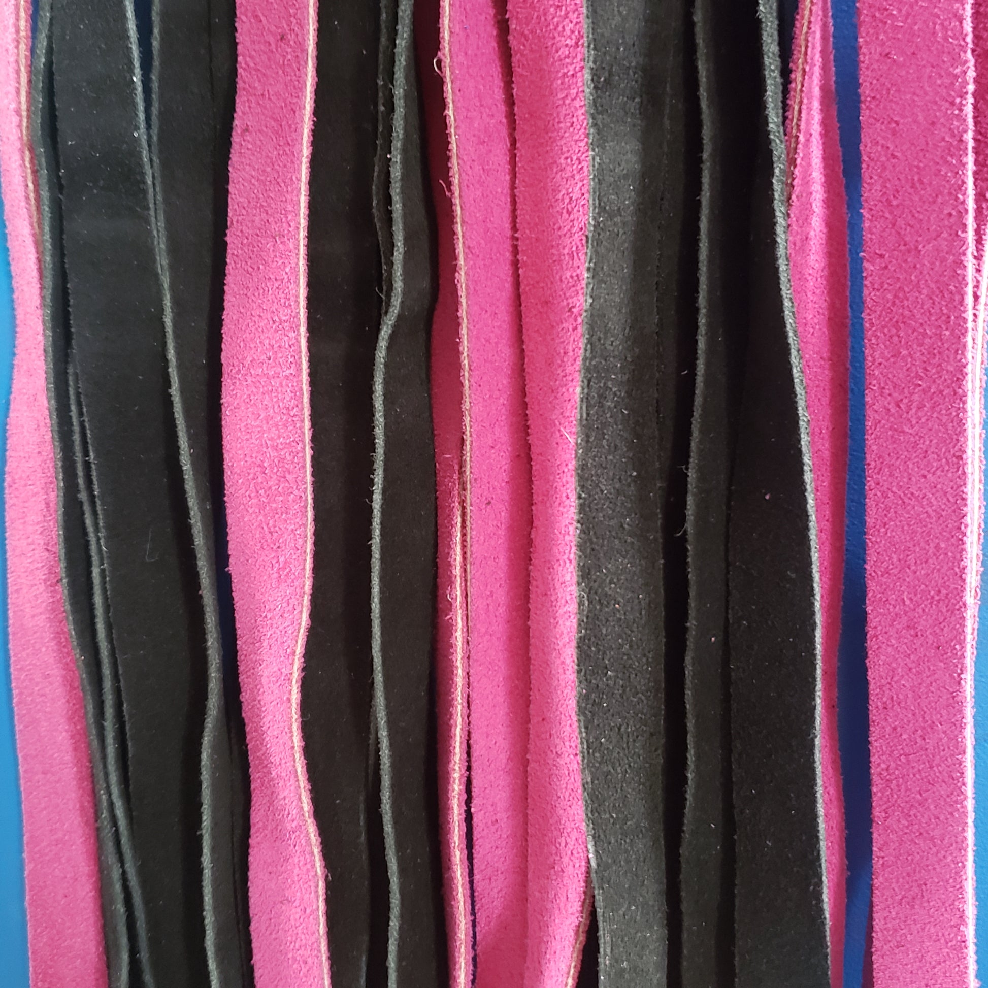 A closeup of the fuchsia and black suede finger loop flogger.