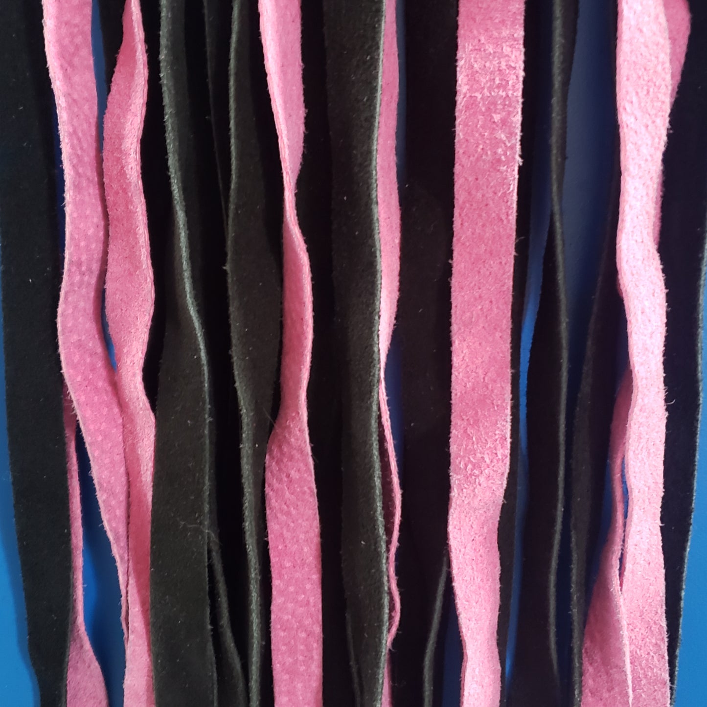 A closeup of the pink and black suede finger loop flogger.