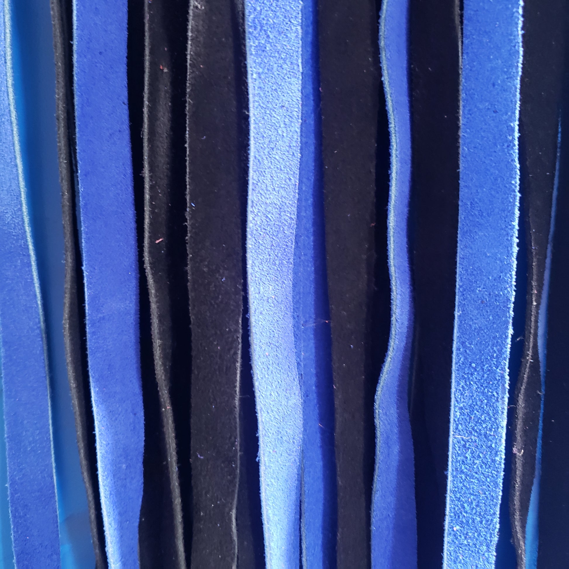 A closeup of the blue and black suede finger loop flogger.