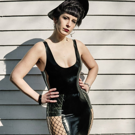 A model showing the front of the black Latex Tank Top with the fishnet panel mini skirt.