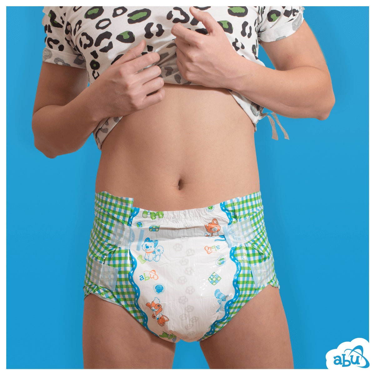 Front view of diaper on model with puppy print on white on center and green/white plaid print on sides.
