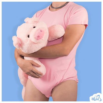 Front view of model wearing baby pink diapersuit with disposable diaper worn underneath and holding a stuffed pig