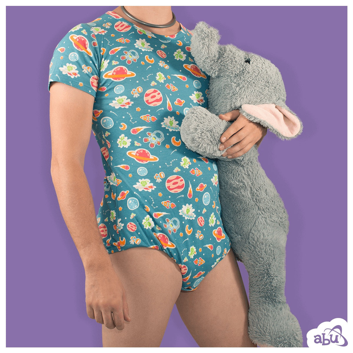Front view of model wearing space print diapersuit with disposable diaper worn underneath and holding a stuffed elephant.