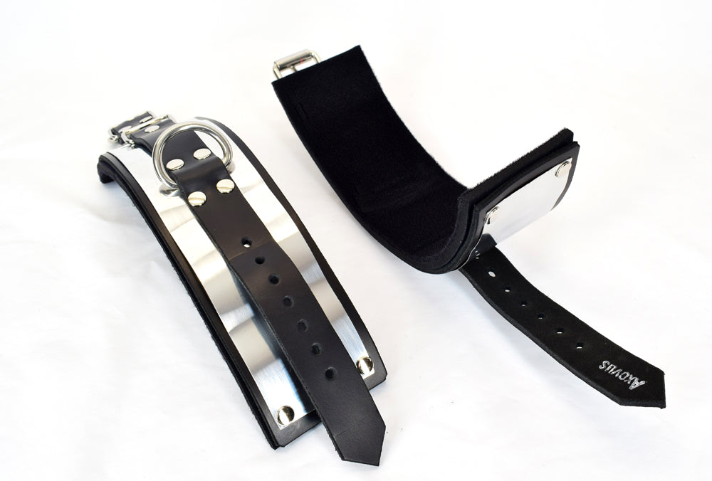 Metal band bondage cuffs laid out one right side up showing buckle closure eyelets, other showing inside padding of cuffs, against white background