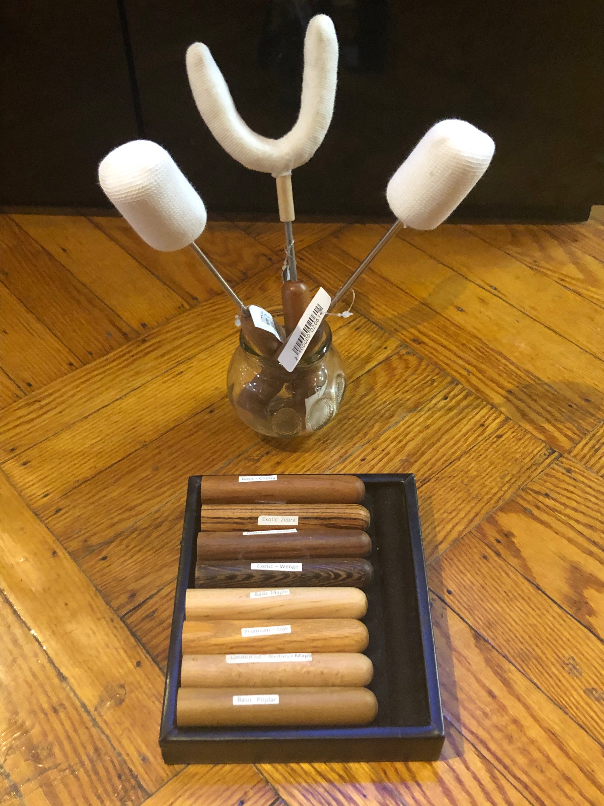 Three Fire Massage Torches sitting upright in a fire cupping glass. There is a box with several wood handles displayed inside.