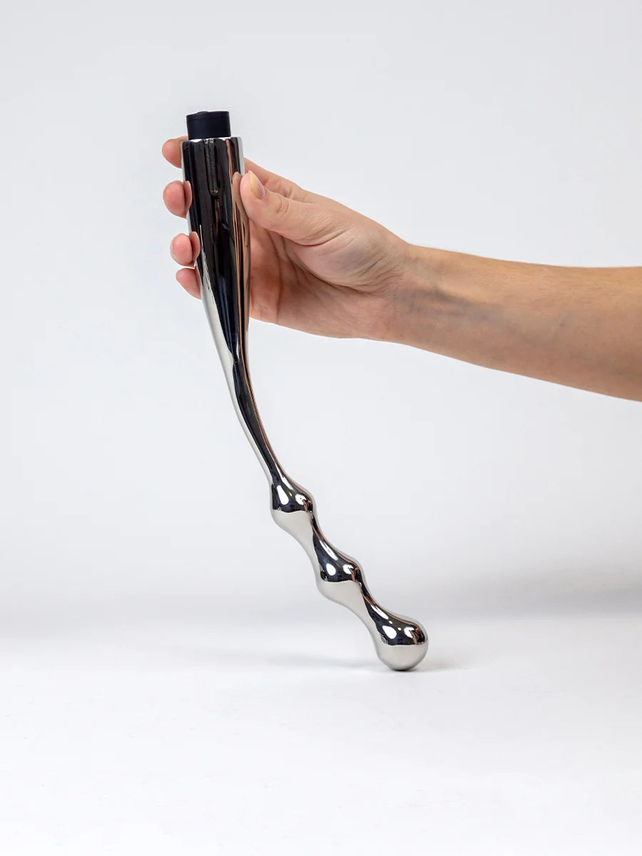 A model's hand holding the Slide Stainless Steel Vibrating Dildo Set.