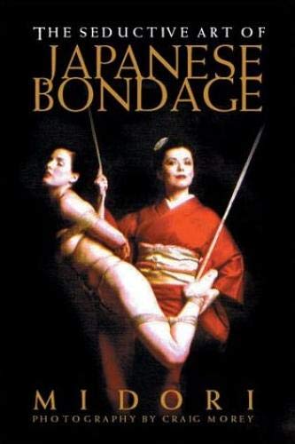 The front cover of Seductive Art Japanese Bondage Midori. Midori standing in front of a black background behind a model that is tied up and suspended with one foot in the air.  The title is printed across the top of the book.