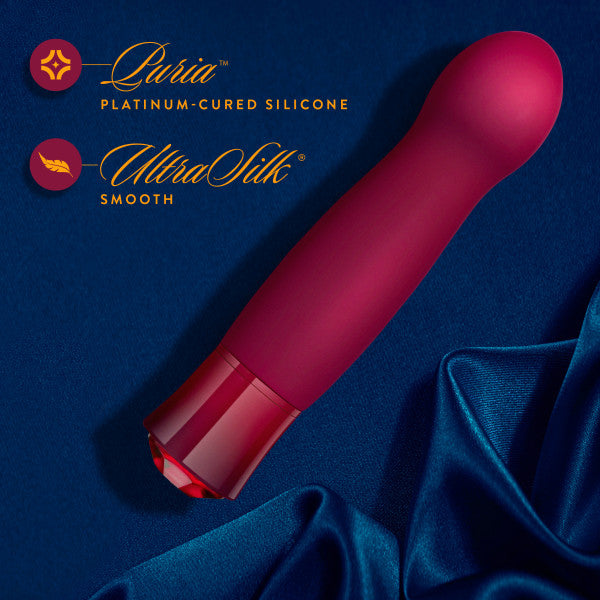 A graphic of the Oh My Gem Classy Garnet Vibrator lying on its side on blue silk next to a description of its materials.