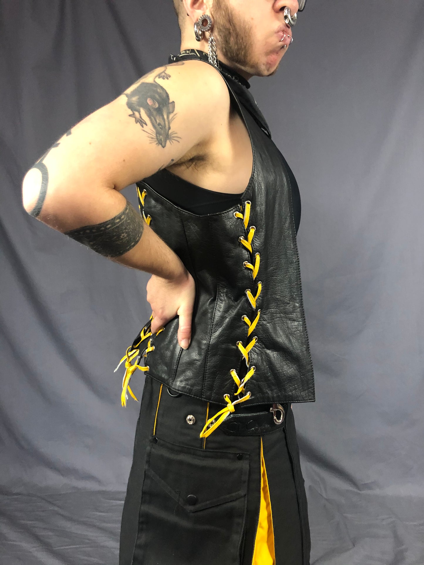 Right view of front & back lace cowhide bar vest with yellow laces, matched with a black kilt with yellow panels.