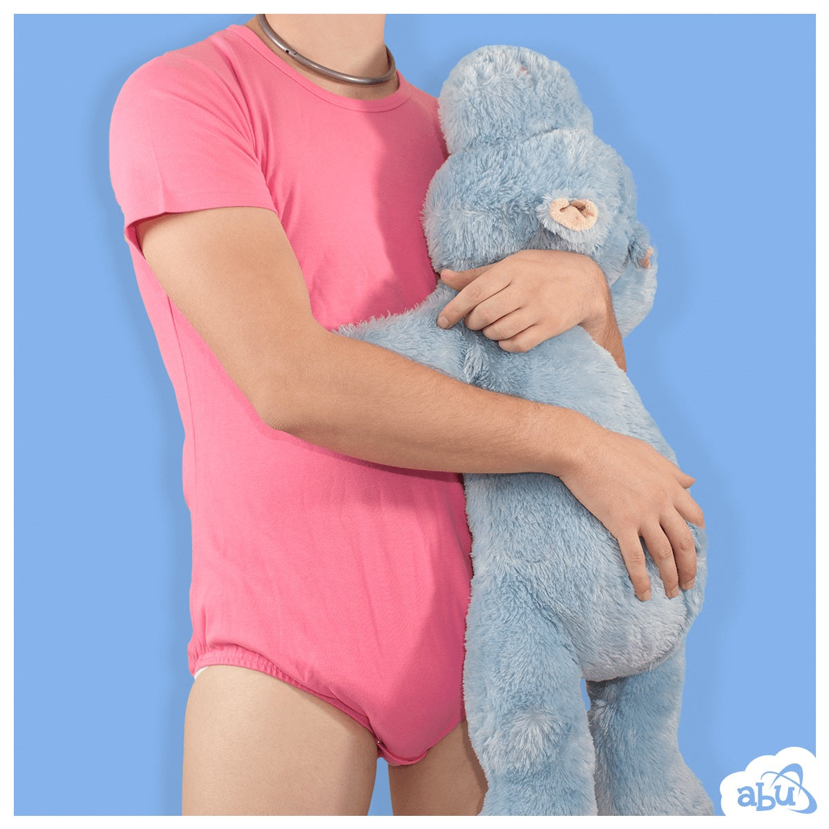 Model wearing pink diapersuit, with disposable diaper worn underneath, holding a stuffed hippo