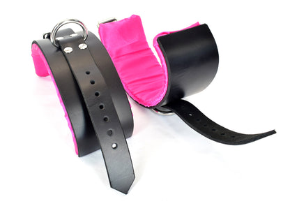 Black with Pink satin lined bondage cuffs; one right side up showing D-ring and closure strap, the other showing the pink satin lining.