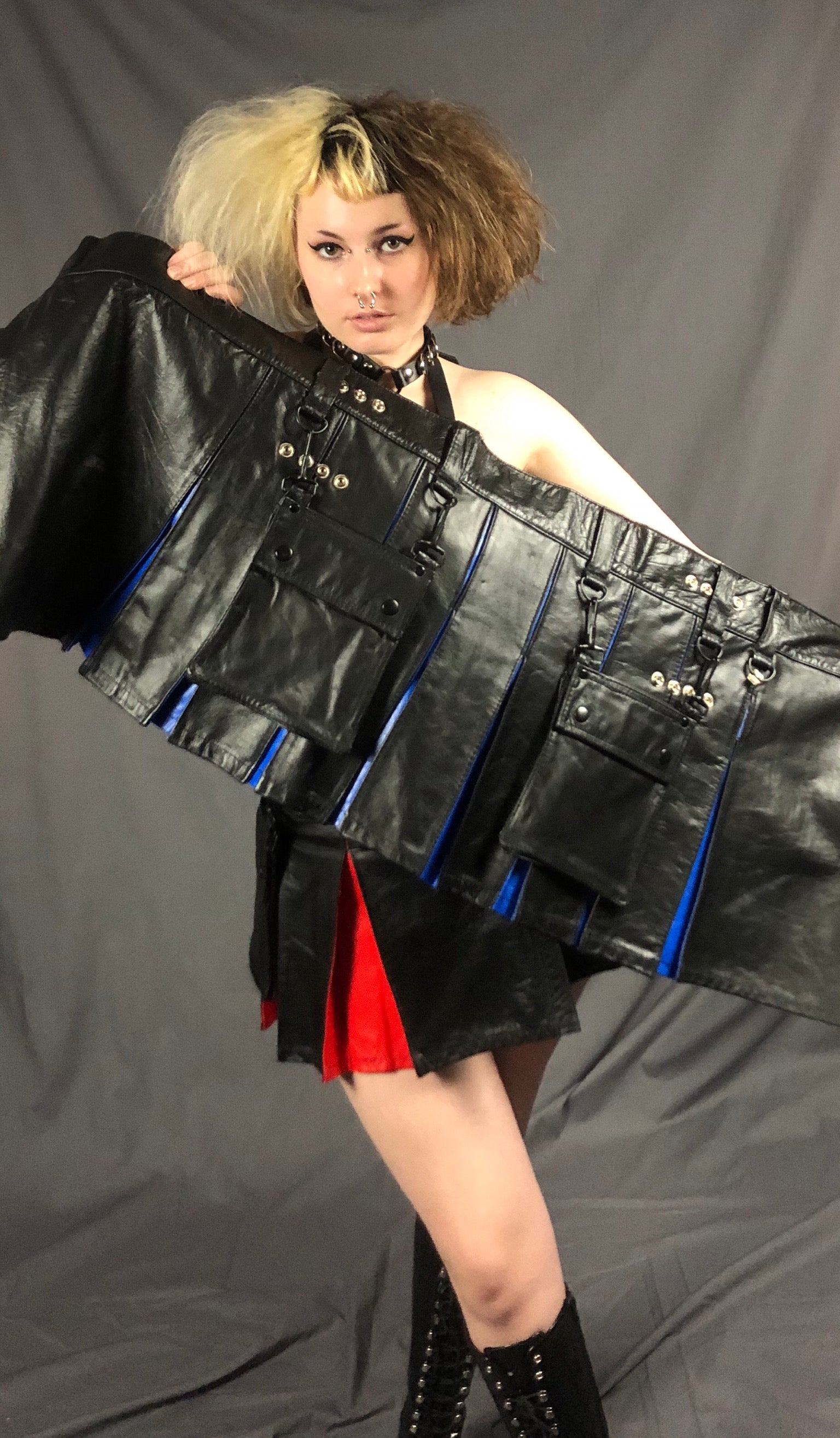 Model holding up the black and blue Mini Cowhide Contrast Pleat Heritage Kilt.