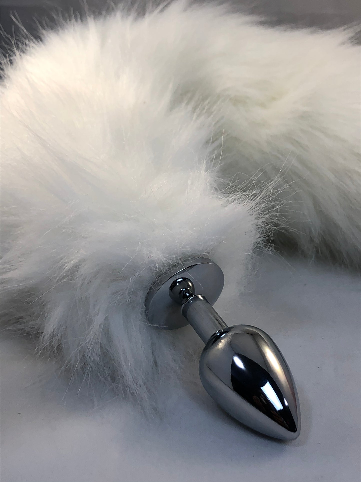 Faux white fur, with pink tip. Closeup on the butt plug.