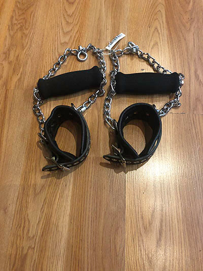 The black pair of detachable grip cuffs on a wooden floor.