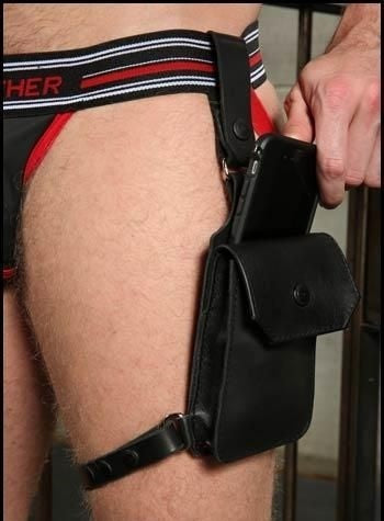 Model putting mobile phone into the Jockstrap Holster Harness attached to a jockstrap and model's left leg.