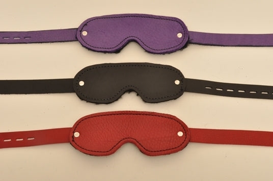 A purple, a black, and a red blindfold lying parallel to each other.