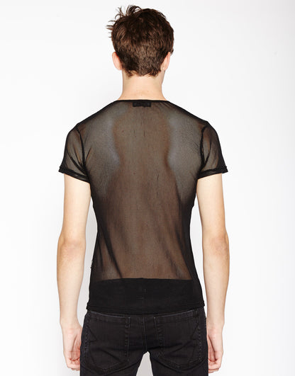 Model wearing the black Short Sleeve Fishnet T-Shirt with black pants, rear view.