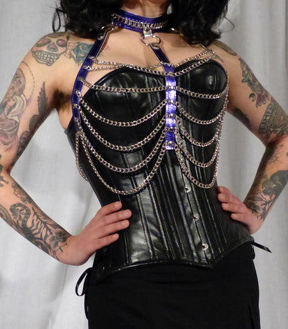 A model wearing the purple leather and chain three column halter harness over a black bust corset.