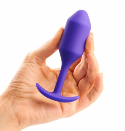 B-Vibe Vibrating Weighted Anal Snug Plug in purple in model's hand.