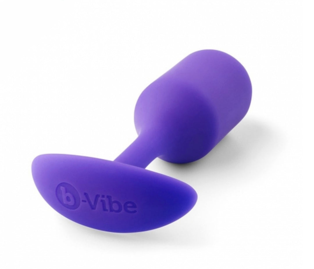 B-Vibe Vibrating Weighted Anal Snug Plug in purple lying on its side.