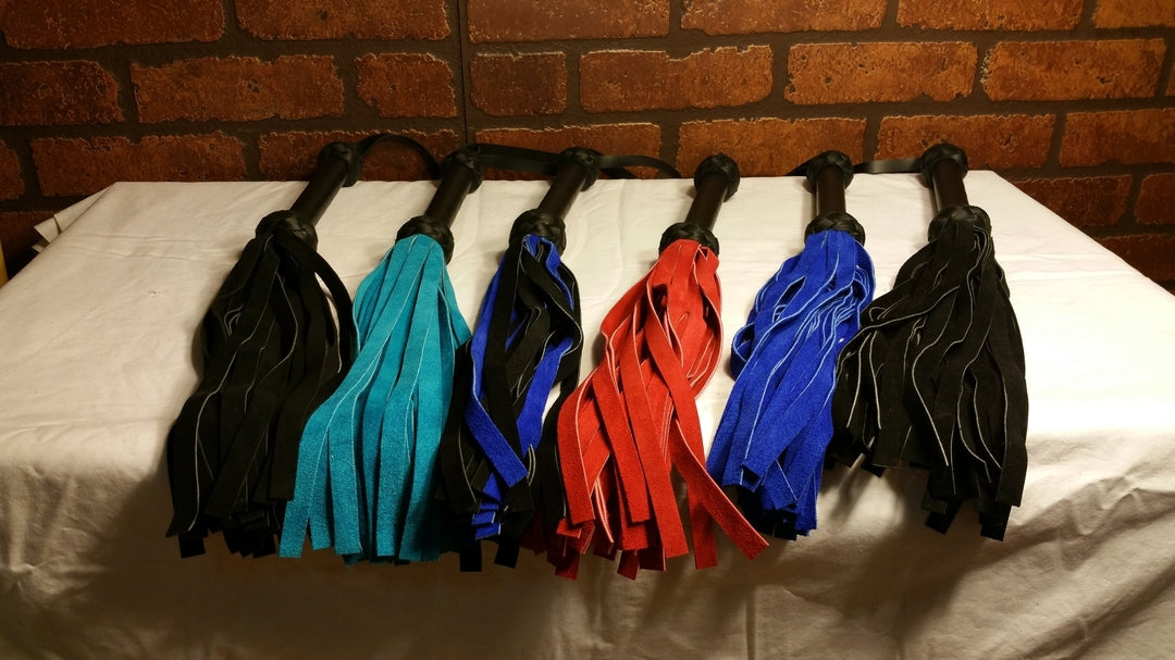 Six Lite Line Basic floggers in various colors, lined up next to each other.