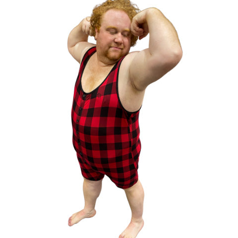 Model wearing plaid bamboo tank onesie, flexing arms, front view.