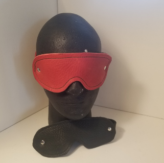 A read leather blindfold on a styrofoam head.