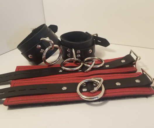 Pair of black Basic Fleece Wrist Restraint Cuffs displayed buckled, and a red pair displayed laying flat.