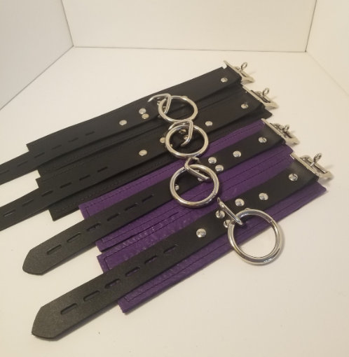Pair of purple Basic Wrist Restraint Cuffs and a pair of black Basic Ankle Restraint Cuffs displayed laying parallel to each other.
