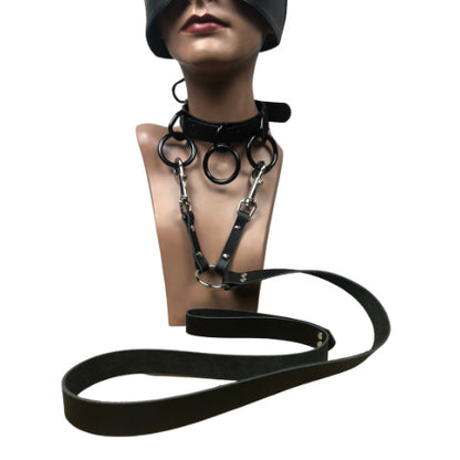 Closeup of mannequin head with leather half mask and 3 ring choker collar attached to a double leather leash.