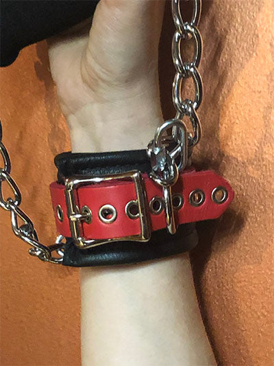 A close up of the buckle closure of detachable red grip cuff.